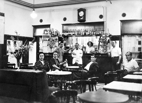 Retrat d'un grup de persones a l'interior de l'Exprés Bar, a la Rambla de la Llibertat. Darrera la barra, Paulina Pedrós entre els clients i una cambrera. 1939-1940