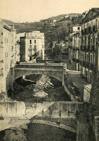 Vista des d'un punt elevat del riu Galligants al seu pas pel barri de Sant Pere. En primer terme, un aqüeducte, en segon terme, el pont del carrer de la Barca i darrera seu, el pont del carrer del Llop. 1905-1911
