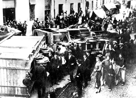 Descarrilament del tren de Palamós a l'altura del número 105 del carrer de Pont Major. S'observa un grup de persones mirant el vago descarrilat i nombrosos curiosos al voltant. 1920-1930