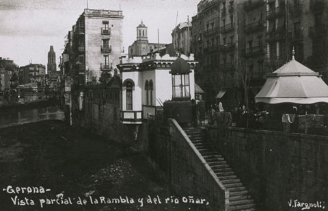 Rambla de la Llibertat des del pont de Pedra. Al centre s'hi observa el quiosc-urinari al costat del Dispensari Municipal, i a la dreta el quiosc de periòdics. 1920