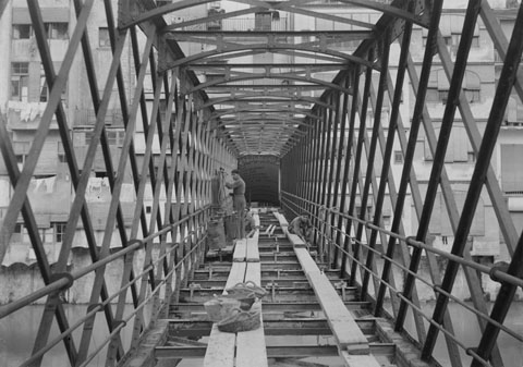 Obres al pont de les Peixateries Velles. S'observen els obrers treballant en la substitució de la fusta del paviment, en el marc de les obres de reparació dutes a terme per la casa constructora Torras de Barcelona. 1923