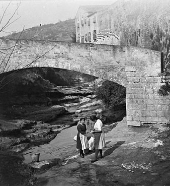 Dones rentant la bugada a les ribes del riu Galligants, a l'altura del pont de la font d'en Pericot. A la dreta, el monestir de Sant Daniel. 20/02/1921