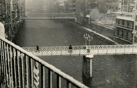 Vista del riu Onyar i les cases del riu després d'una nevada. En primer terme el pont de Sant Agustí, que va ser substituït per un de nou el 1973. Al fons el pont de les Peixateries Velles. 1960-1970