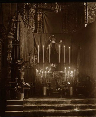 Vista parcial d'un altar ornamentat per la celebració de la Setmana Santa a l'església de Sant Feliu. A la dreta de la imatge s'observen dues dones resant. 1923