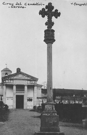 Vista parcial del cementiri de Girona amb la creu de pedra en primer pla. Al fons, la capella neoclàssica. 1911-1936
