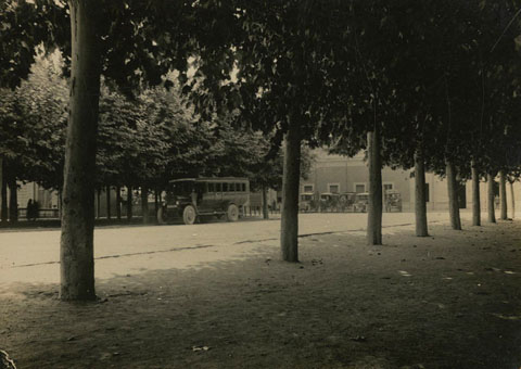 Autobús aparcat a la plaça del Carril. Al fons, l'estació del tren. 1935-1940