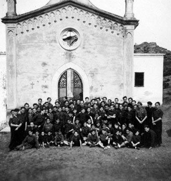 Retrat de grup dels joves del Frente de Juventudes davant la Capella de la Mare de Déu dels Dolors el Divendres Sant. Al centre mossèn Ferran Forns. 1940