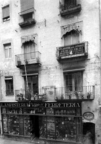 Façana d'un edifici a l'Argenteria, on s'observa  l'aparador de la lampisteria-ferreteria 'Casa Priante', a la planta baixa. En un dels balcons hi ha el rètol de la perruqueria de dones 'Julio Palou'. 1933