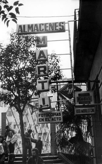 El pont de les Peixateries Velles vist des del carrer de les  Hortes. En primer terme s'observa el cartell dels establiments Almacenes Martí i Foto Cine Morillo. 1970