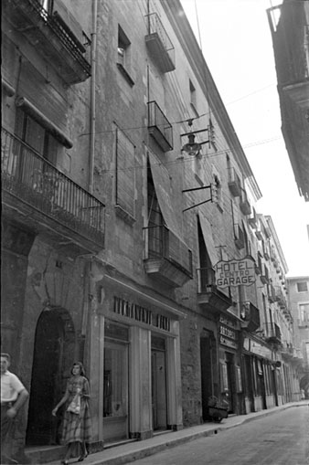 El carrer Ciutadans amb rètols comercials: Permanente Henri, Perfumeria Torrellas, al mig Hotel Centro. 1957