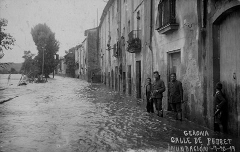 Vista del carrer Pedret inundat pel desbordament del riu Ter. Al fons sobresurt l'església del Pilar. 1919