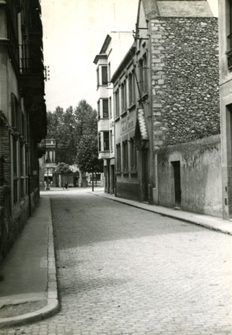 El carrer del Nord després de la col·locació de les llambordes. Vista amb la Gran Via Jaume I al fons. A la dreta, la desapareguda Escola de Dibuix. 1952