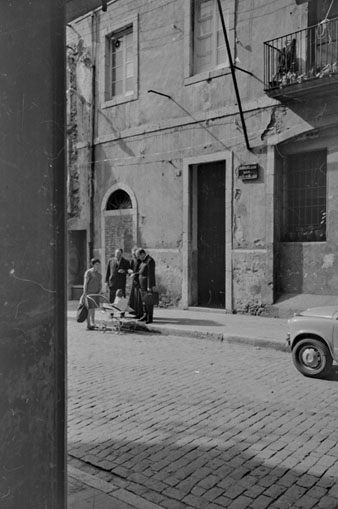 Diada de Germanor de l'Escolania del Mercadal. Dos homes i mossèn Ferran Forns conversen amb una dona al carrer del Perill, a davant de la Casa de les Aigües. 1965