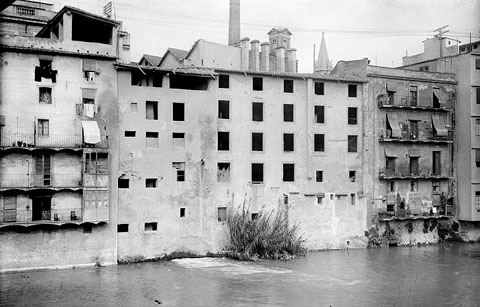 Cases del carrer Santa Clara vistes des del riu Onyar. Al fons es veu la fàbrica Grober, la torre de les Aigües i el campanar neogòtic de l'església del Mercadal. 1925