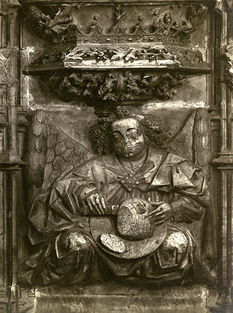 Representació d'un àngel amb el pa senyat en acció de llescar-lo. Detall del retaule de l'altar major de l'església de Santa Maria de Castelló d'Empúries, de la segona meitat del segle XV. 1915