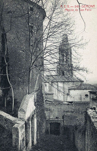 Vista de l'absis i el campanar de l'església de Sant Feliu des de l'espai paral·lel a la muralla que posteriorment ocuparia el passeig Arqueològic. En primer terme a l'esquerra, la torre Cornèlia. 1905-1911
