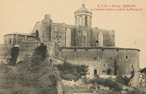 Cara nord de la Catedral de Girona vista des de la pujada de Montjuïc. En primer terme, l'actual passeig Arqueològic i el recinte emmurallat, on destaquen la torre Júlia i la torre Cornèlia. Adossada a la catedral, la torre de Carlemany. 1910-1920