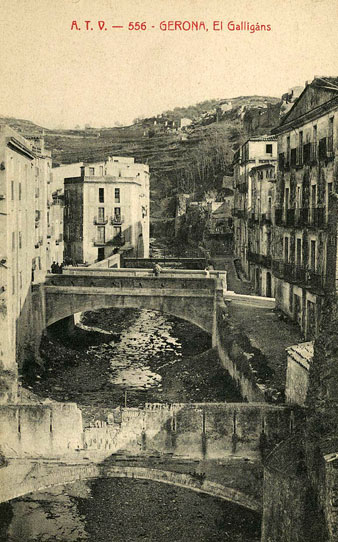 Vista des d'un punt elevat del riu Galligants al seu pas pel barri de Sant Pere. En primer terme, un aqüeducte, en segon terme, el pont del carrer de la Barca i darrera seu, el pont del carrer del Llop. Al fons, Torre Gironella. 1905-1911